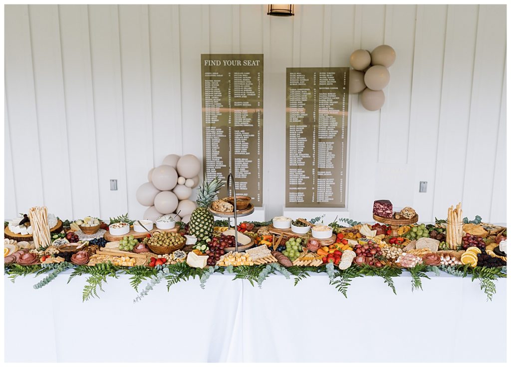 grazing table at wedding in front of acrylic seating chart | Owl & Envelope Custom Wedding Stationery & Signage | charcuterie at wedding, wedding appetizers, balloon install at wedding | via owlandenvelope.com